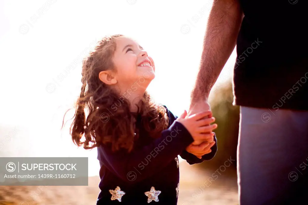 Girl holding father´s hand, looking up