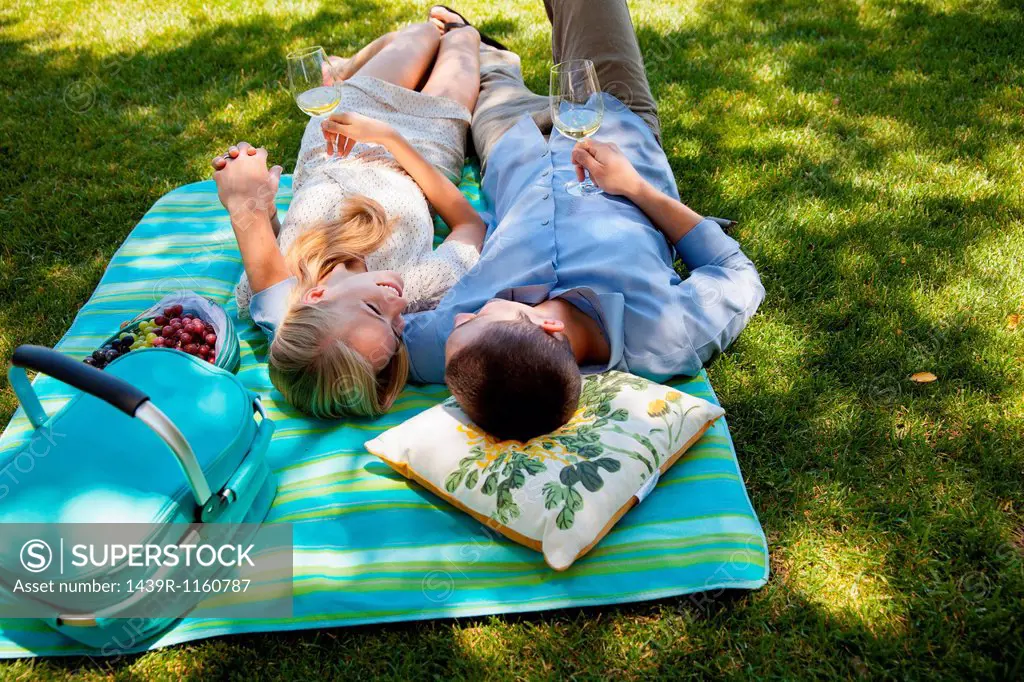 Young couple lying on picnic blanket