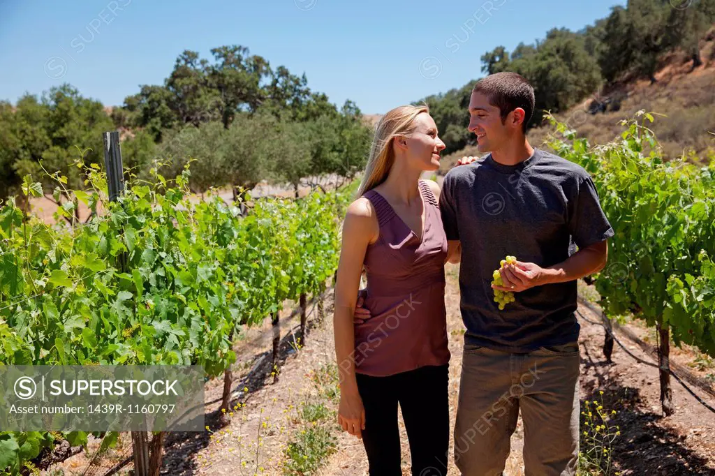 Young couple in vineyard, man holding white grapes