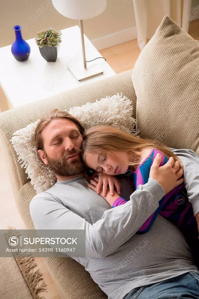 Father and daughter sleeping on couch