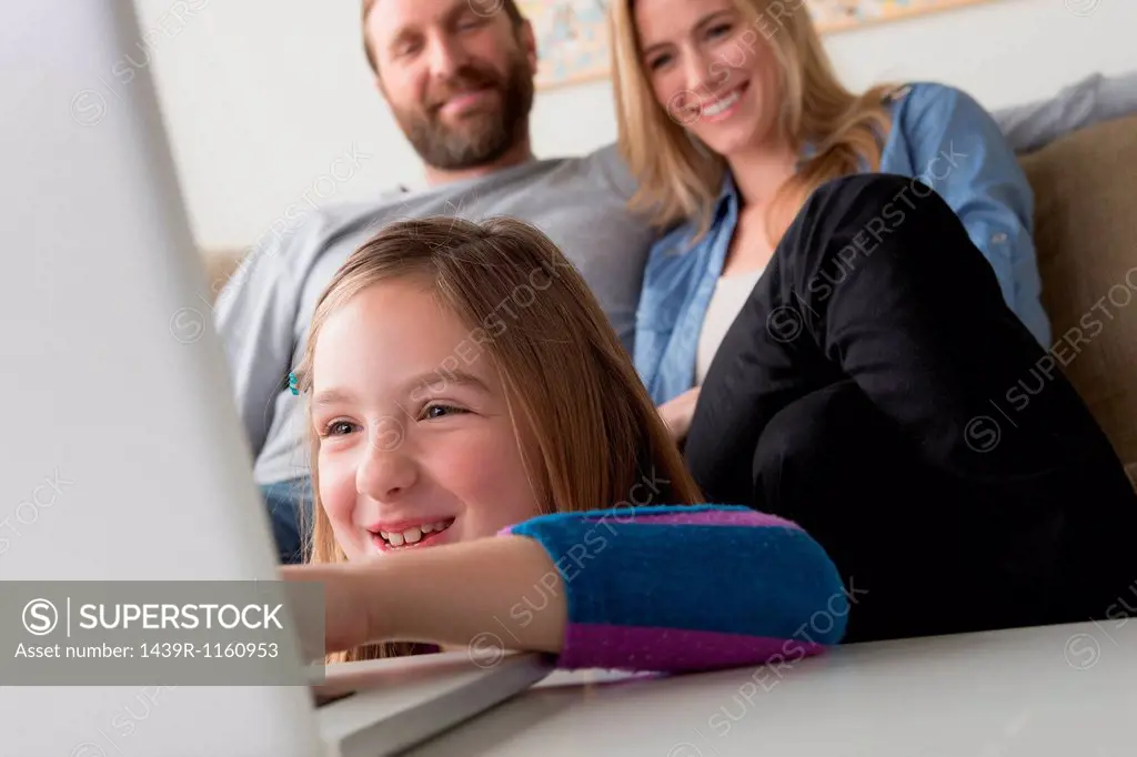 Parents looking at child using laptop