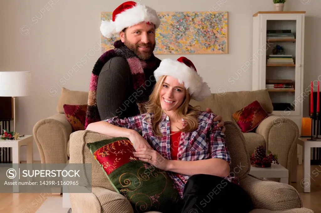 Husband and wife in Santa hat looking at camera