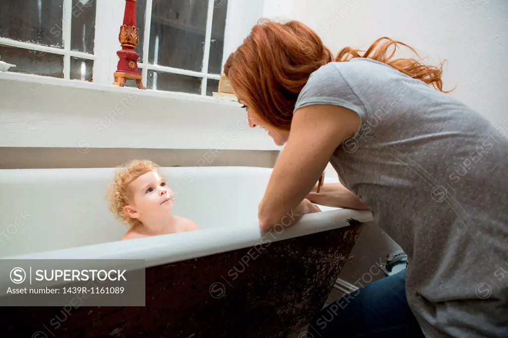 Mother smiling at child in bathtub