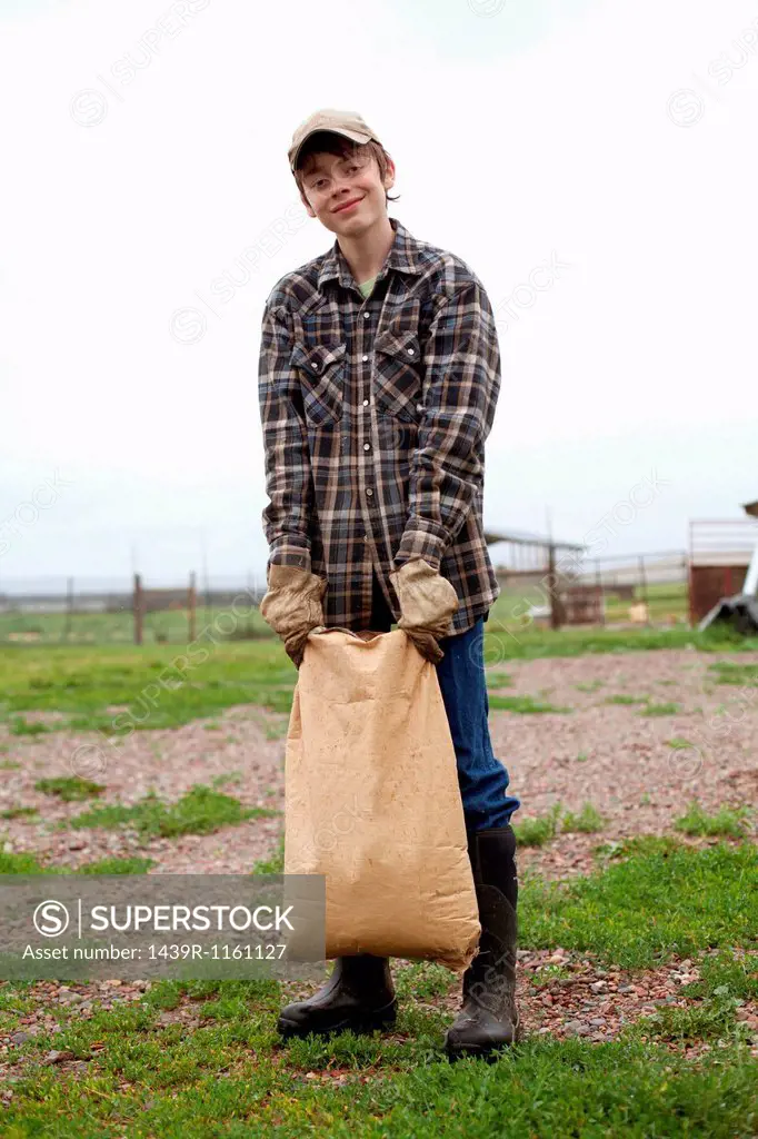 Boy carrying sack of feed