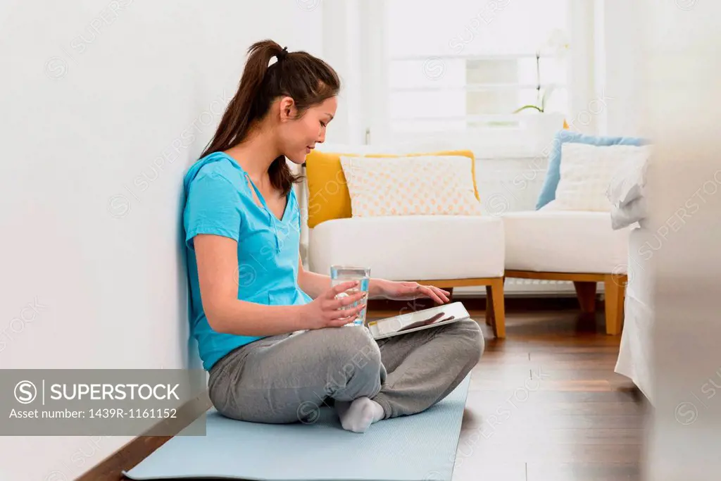 Woman sitting on mat using digital tablet