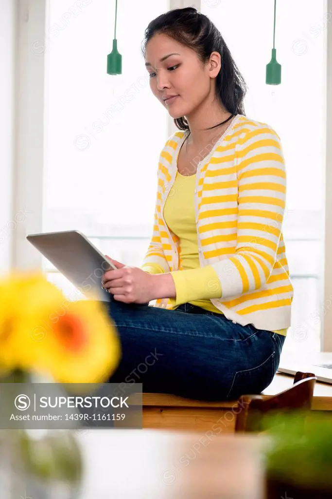 Woman sitting on table using digital tablet