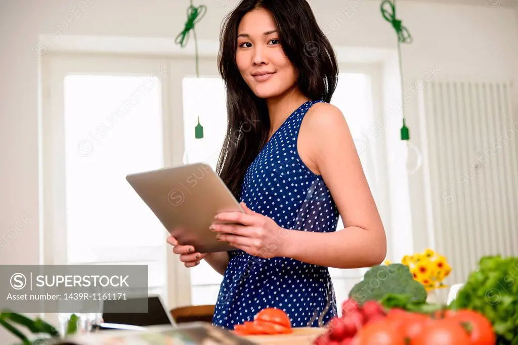 Woman holding digital tablet looking at camera