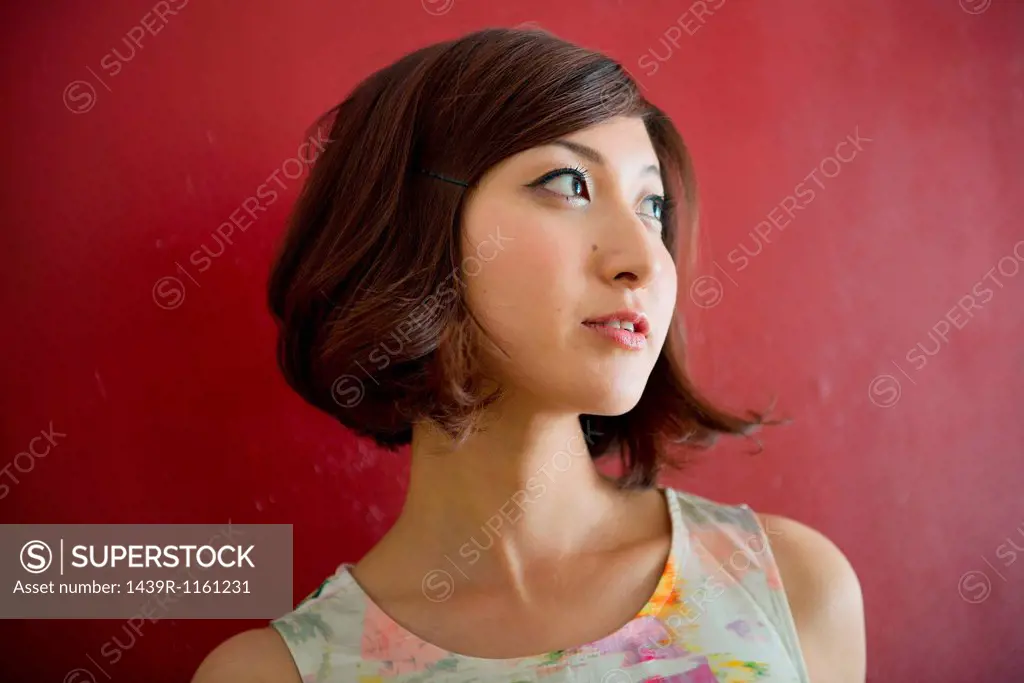 Woman against red wall looking into distance