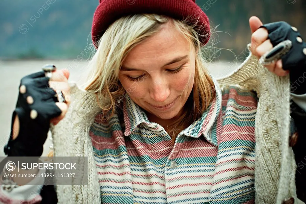 Portrait of woman looking down and holding cardigan