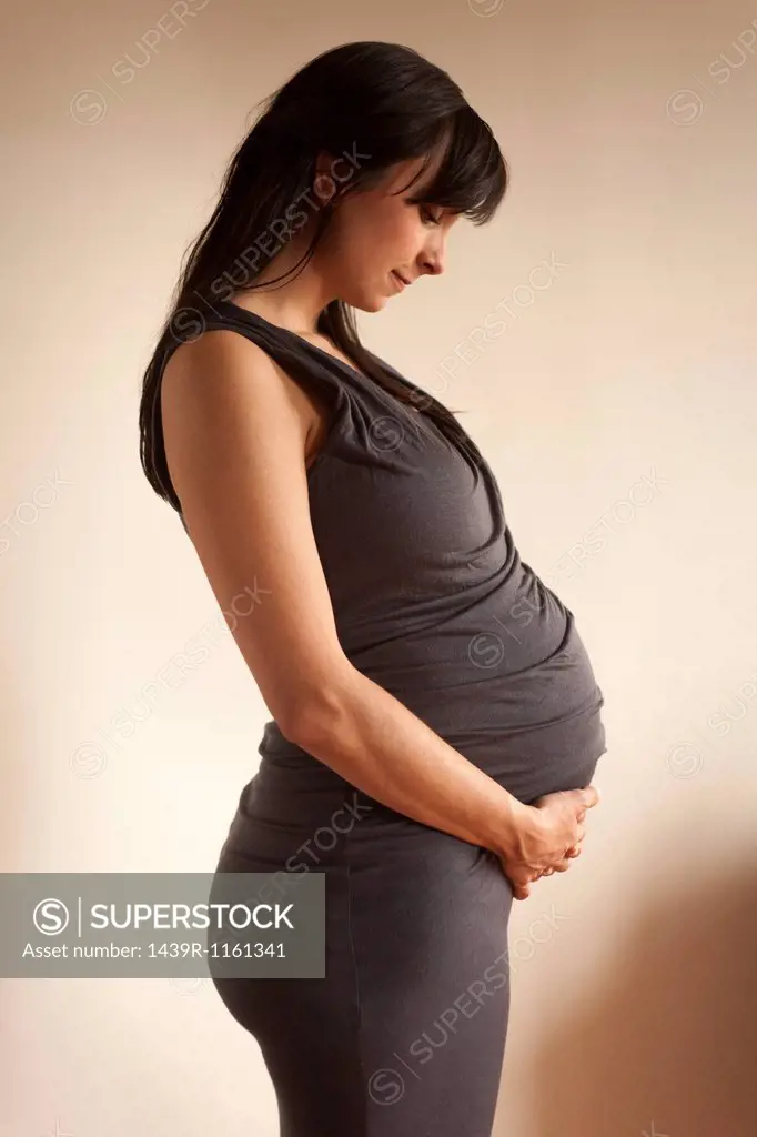 Pregnant woman meditating whilst holding abdomen