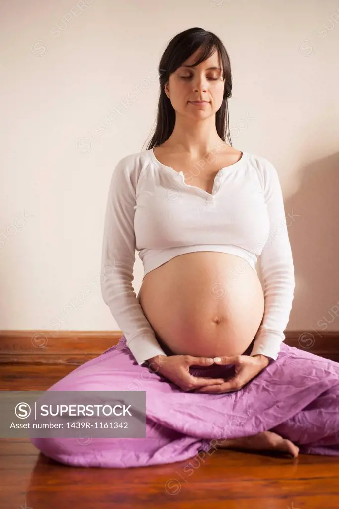Pregnant woman meditating whilst sitting on floor