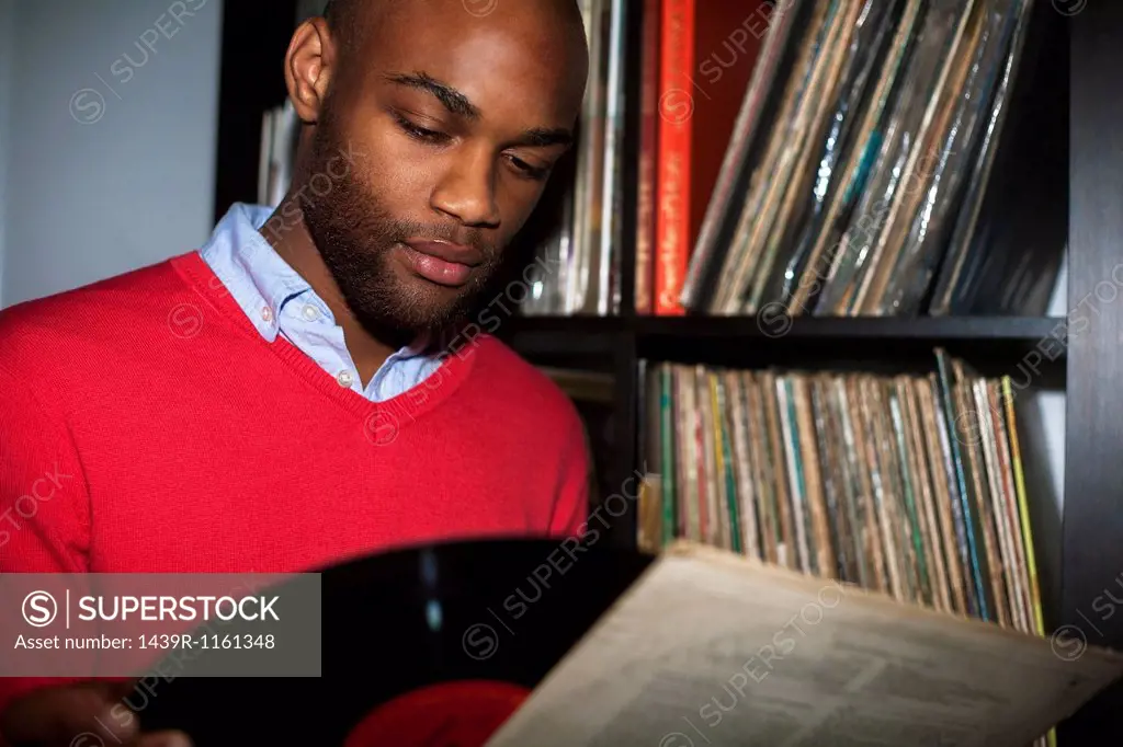 Portrait of young man removing vinyl record from sleeve