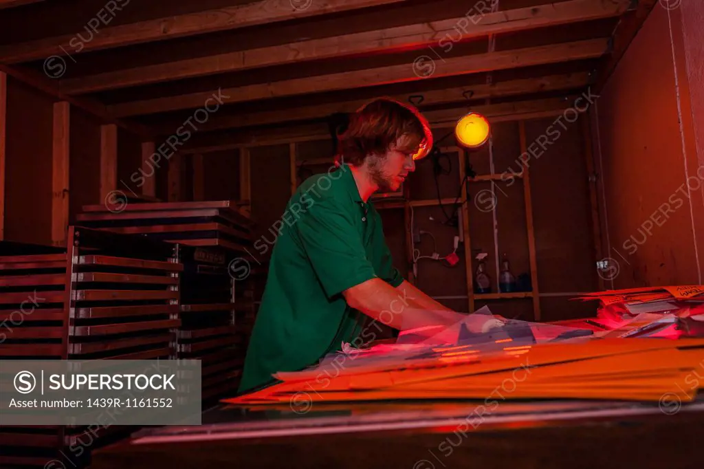 Man working in darkroom in screen printing workshop