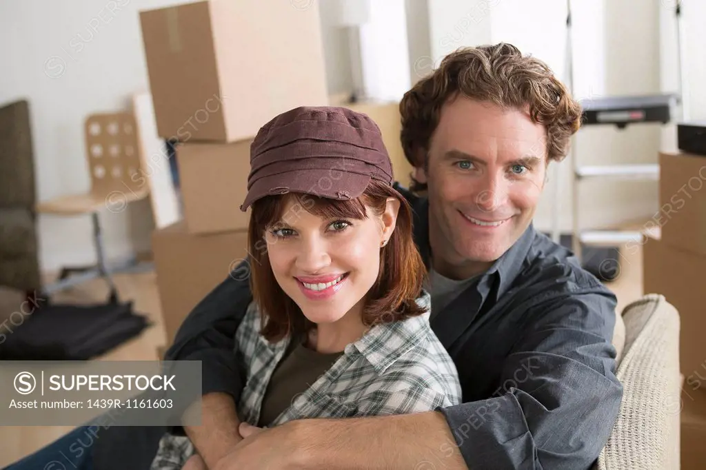 Portrait of couple resting on chair whilst moving home