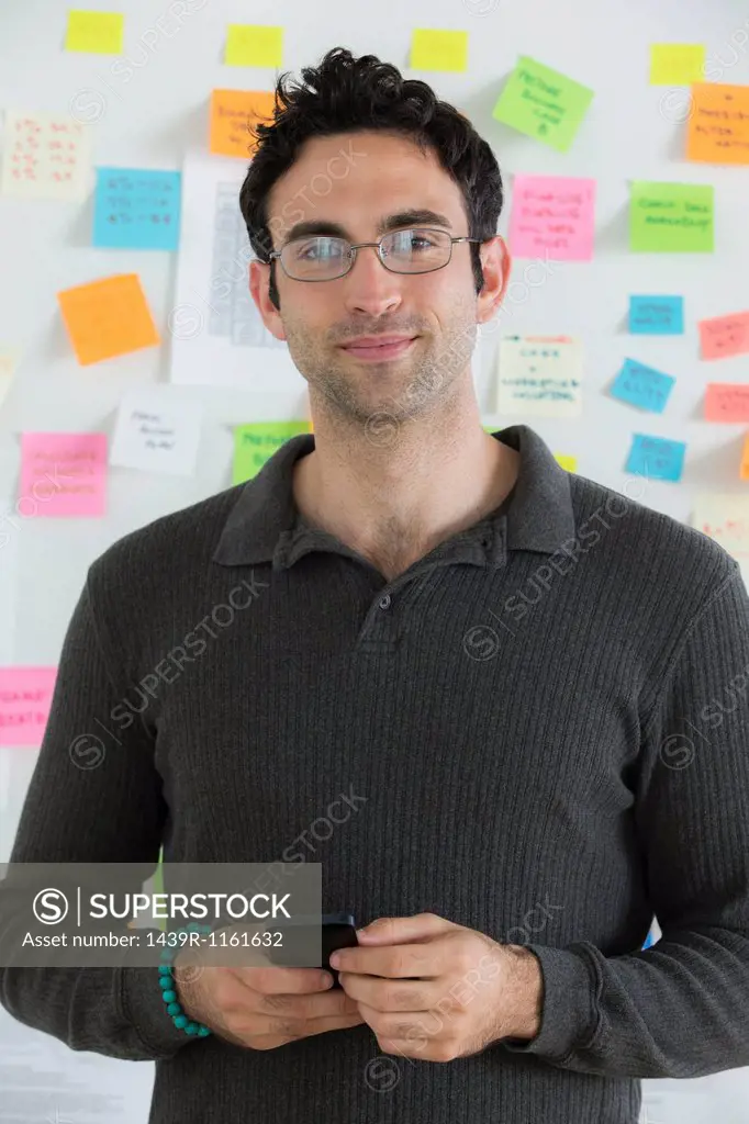 Portrait of male office worker holding mobile