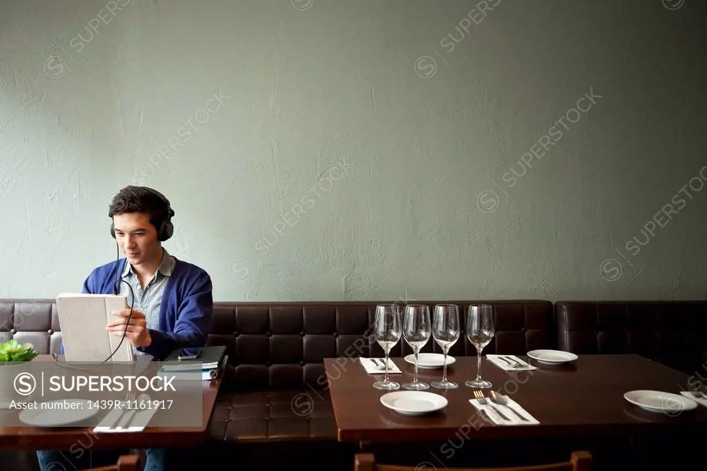 Young man wearing headphones in restaurant