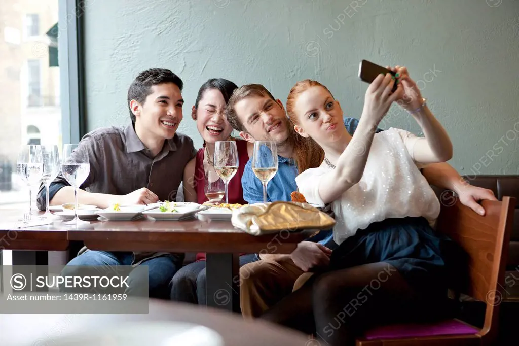 Four friends photographing themselves in restaurant