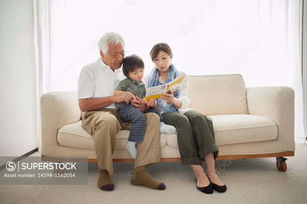 Mother reading to son sitting on grandfather´s lap