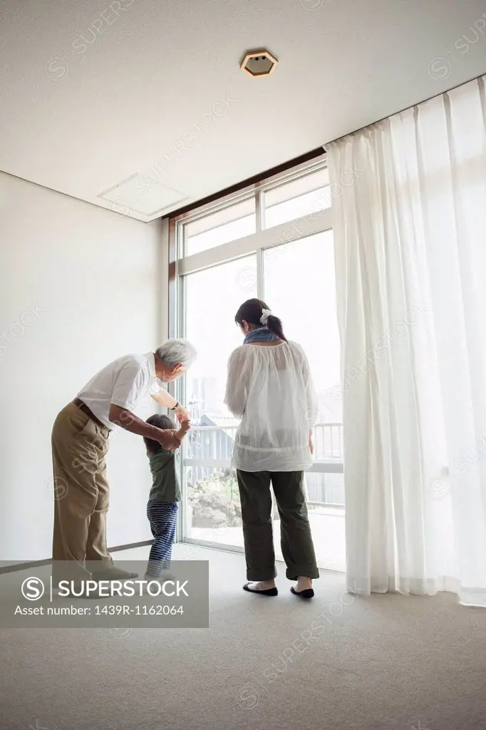 Three generation family standing by window
