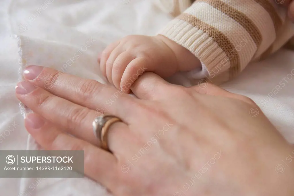 Baby boy holding mother´s hand, close up