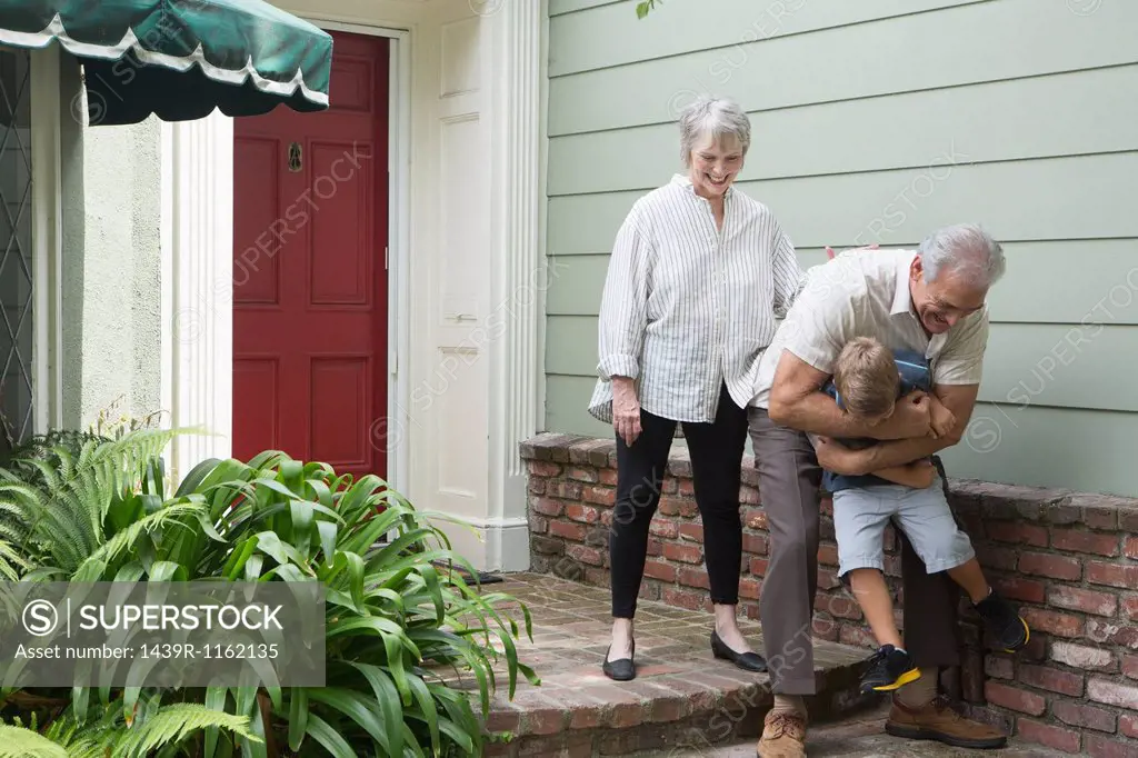 Senior man playing with grandson outside home