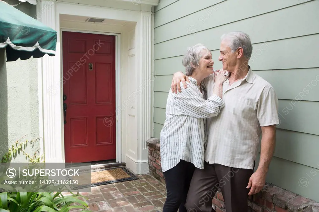 Senior couple smiling together outside house