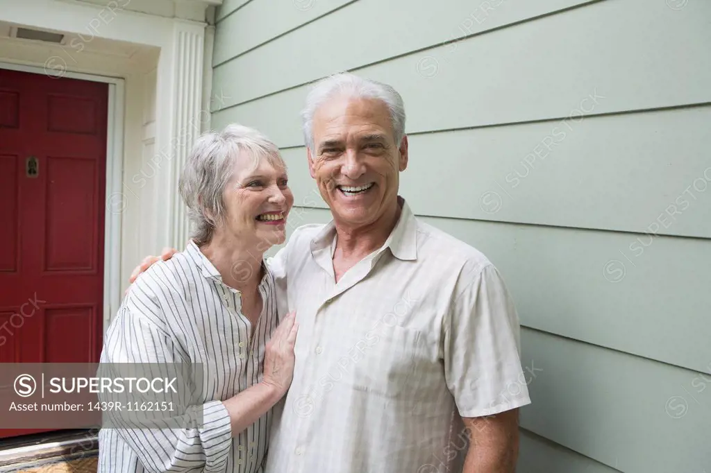 Senior couple smiling together outside house, portrait