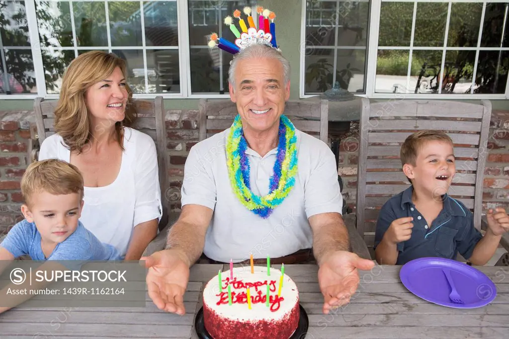 Senior man with birthday cake and family, portrait