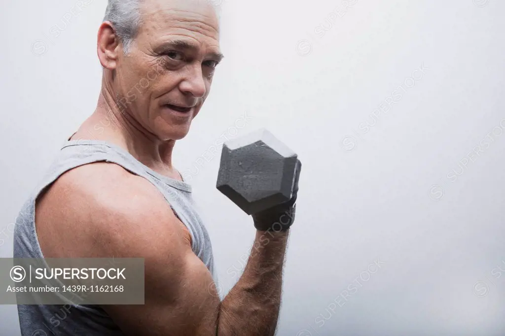 Senior man lifting dumbbell, portrait