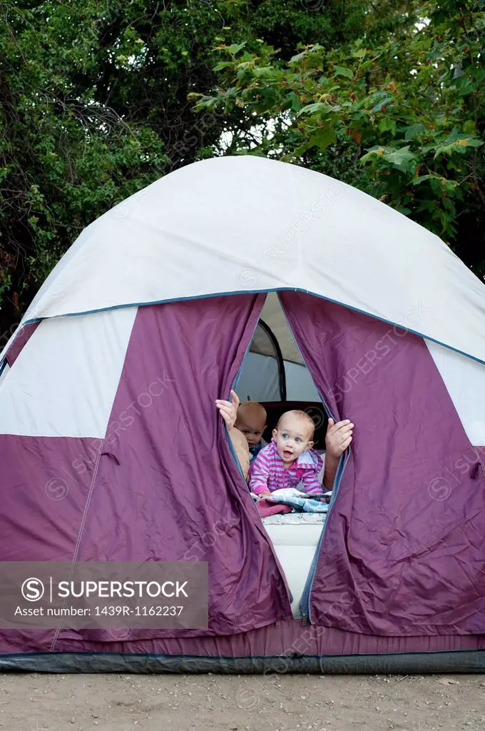 Toddler twins and father peeking out of tent
