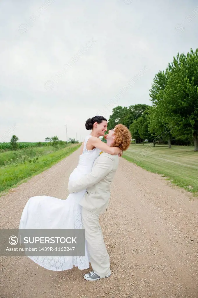 Couple on wedding day hugging on dirt track