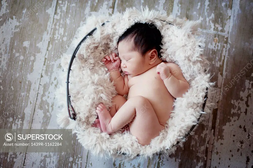 Baby boy sleeping in fur lined basket