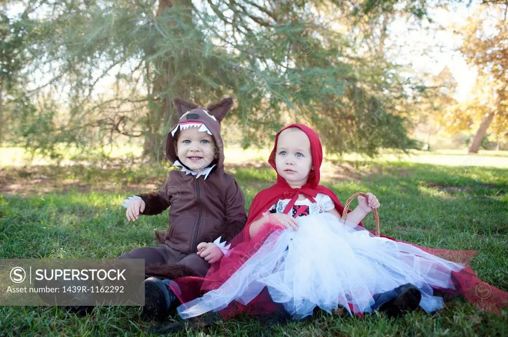 Toddler twins in woods dressed up as red riding hood and wolf