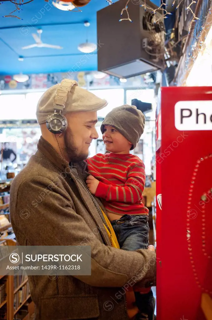 Father holding young son by public telephone