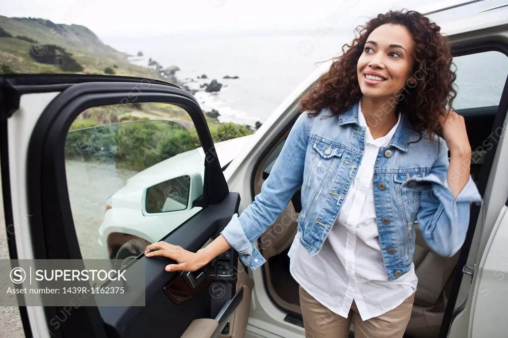 Young woman getting out of car at coast