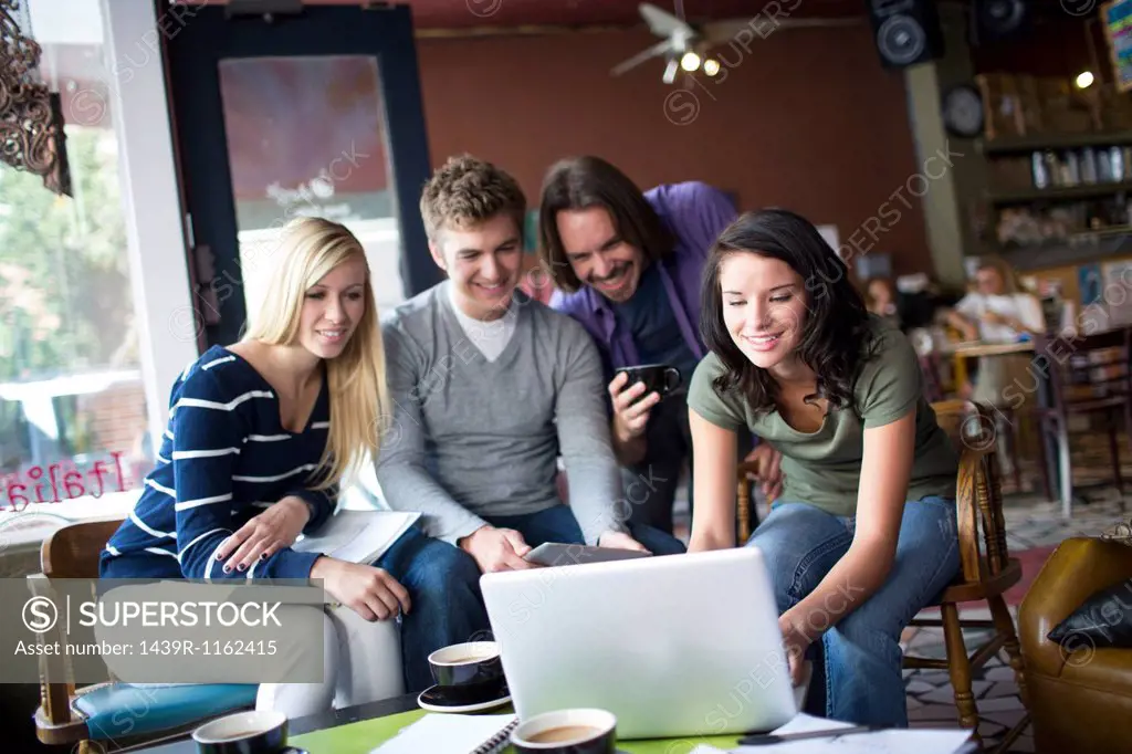 Group of people gathered around computer in cafe