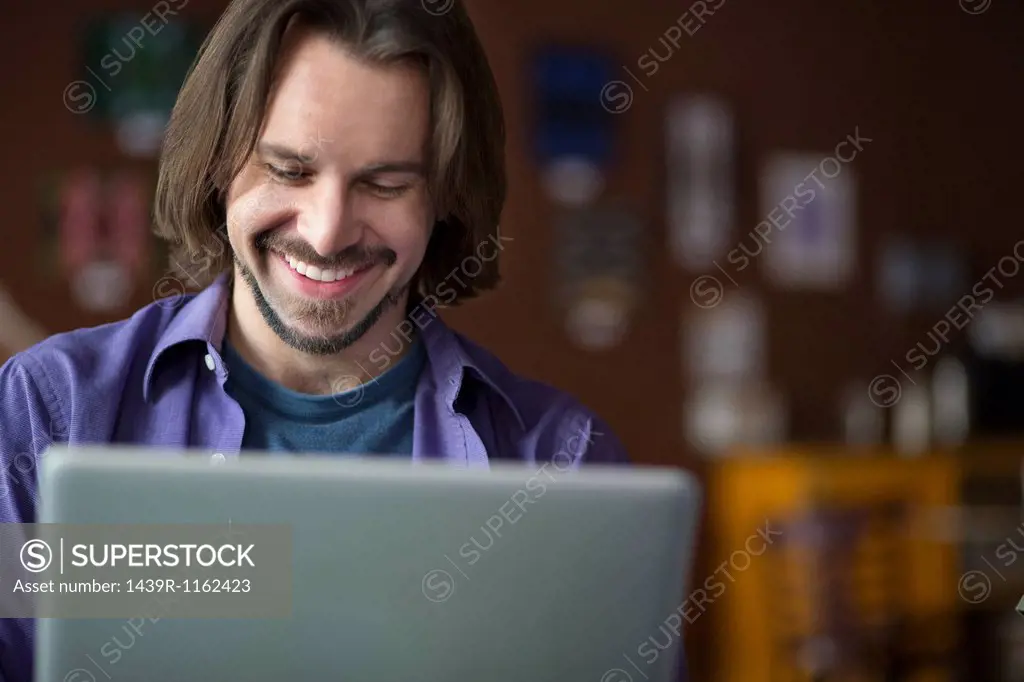Portrait of young man using at computer in cafe