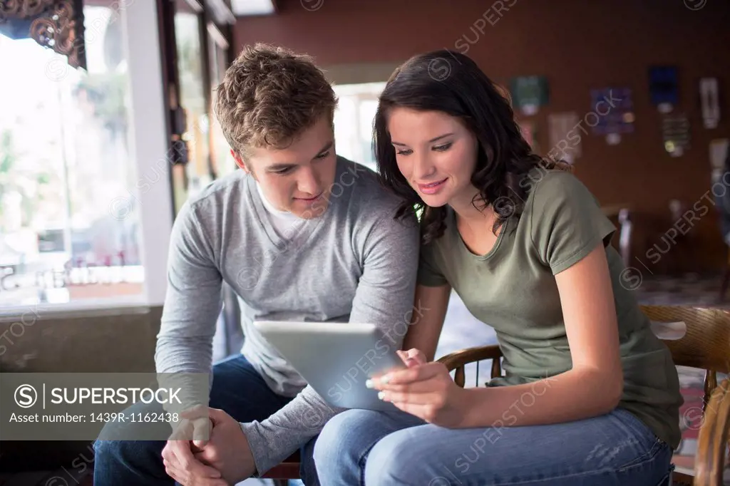 Young couple looking at digital tablet in coffee house