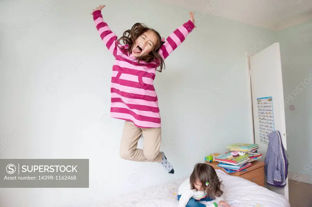 Girl jumping on bed and pulling face