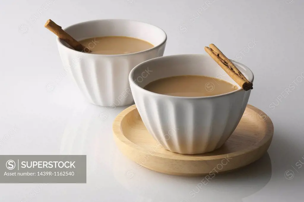 Still life of two bowls of drink with cinnamon sticks