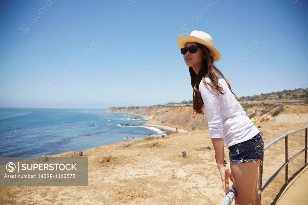 Young woman standing on fence, Palos Verdes, California, USA