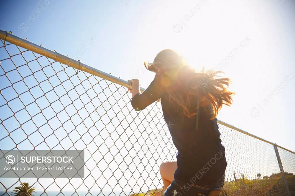 Young woman messing about on wire fence