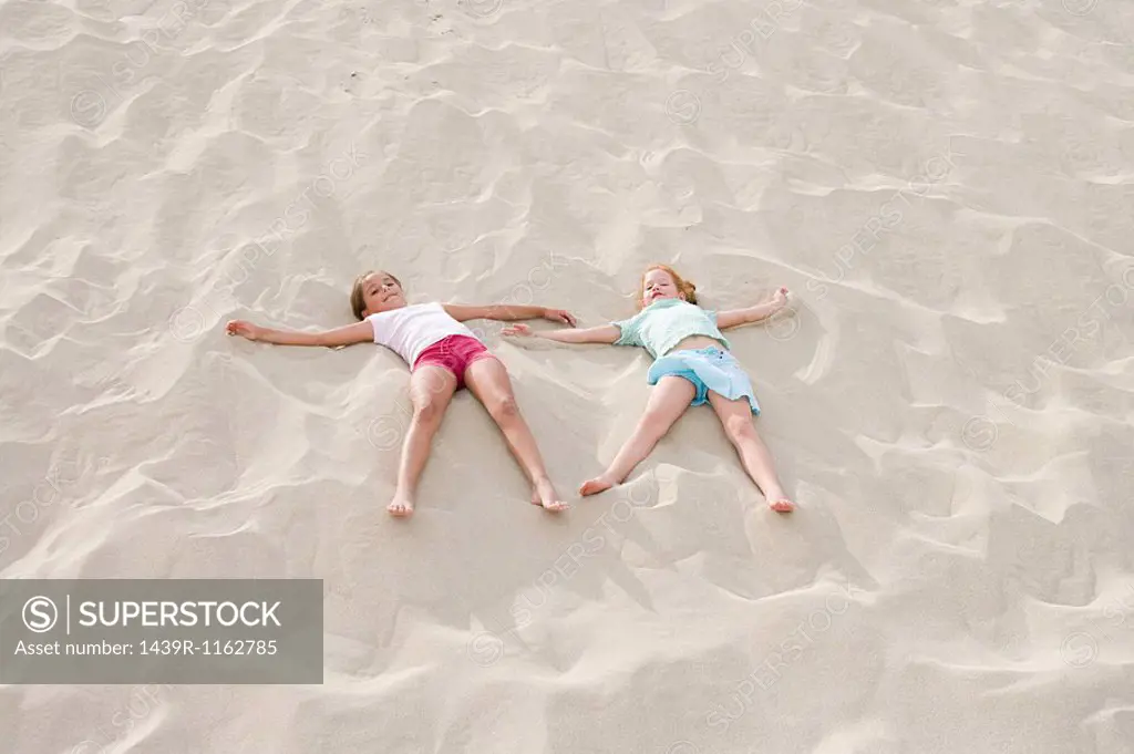 Two girls lying on a beach