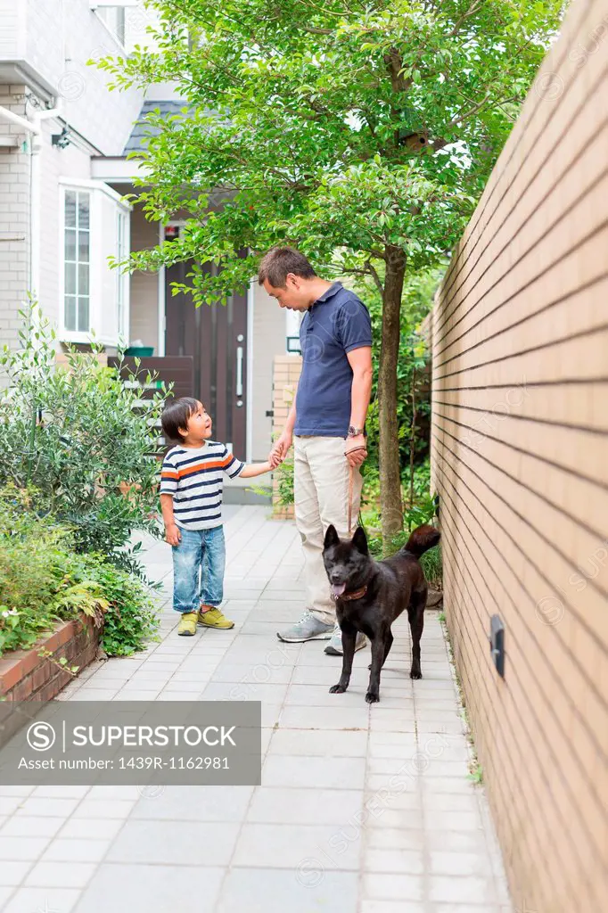 Father and young son on path with dog