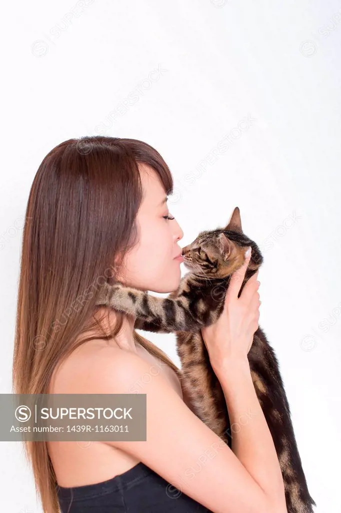Portrait of woman kissing tabby cat