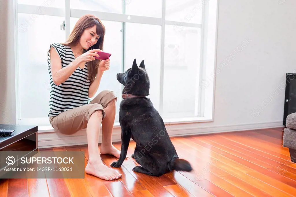 Woman photographing dog on camera phone