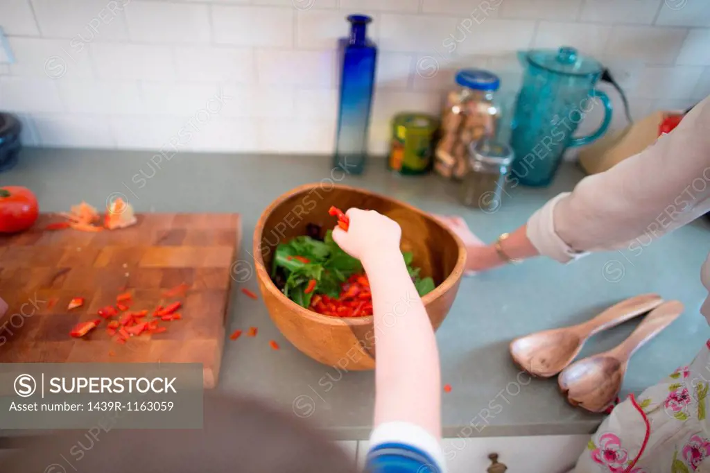 Mother and son preparing salad on kitchen counter