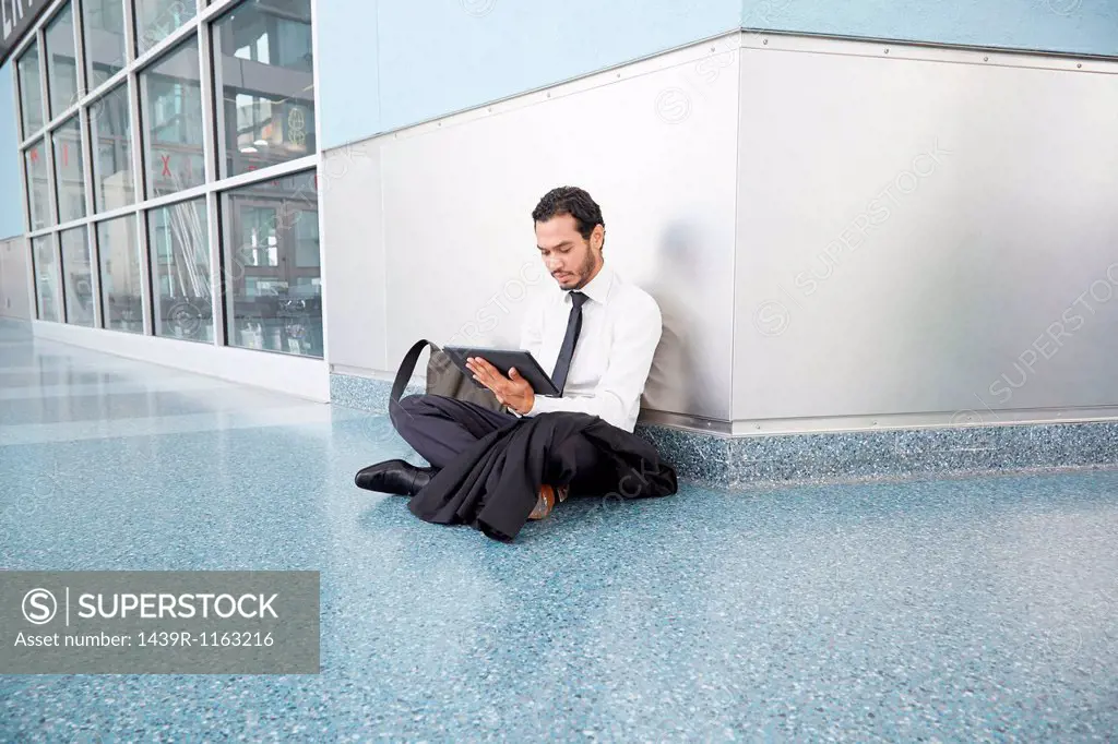 Businessman sitting on floor using digital tablet