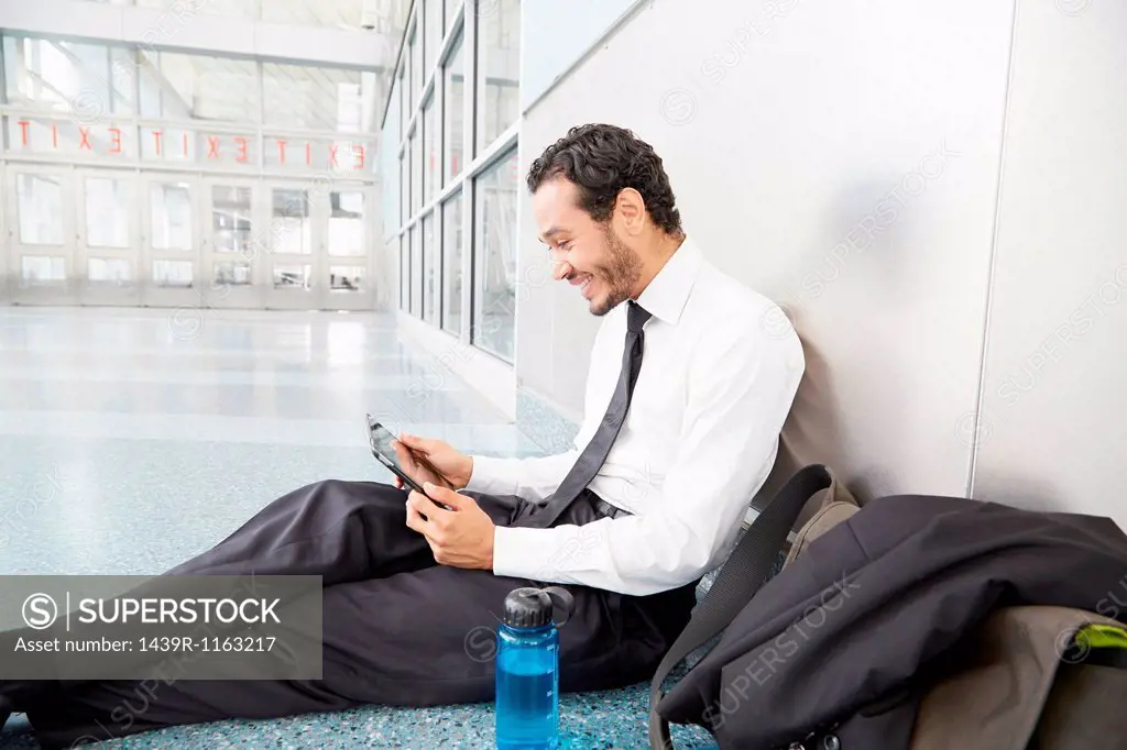 Businessman sitting on floor using digital tablet