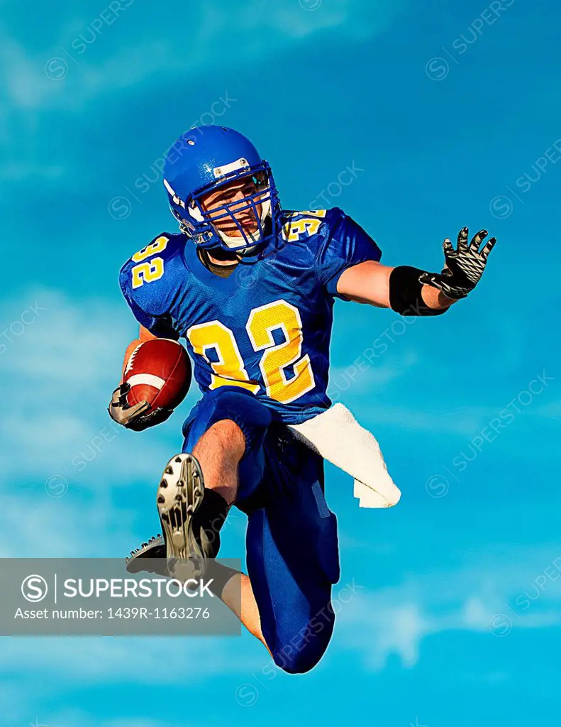 American footballer with ball against blue sky